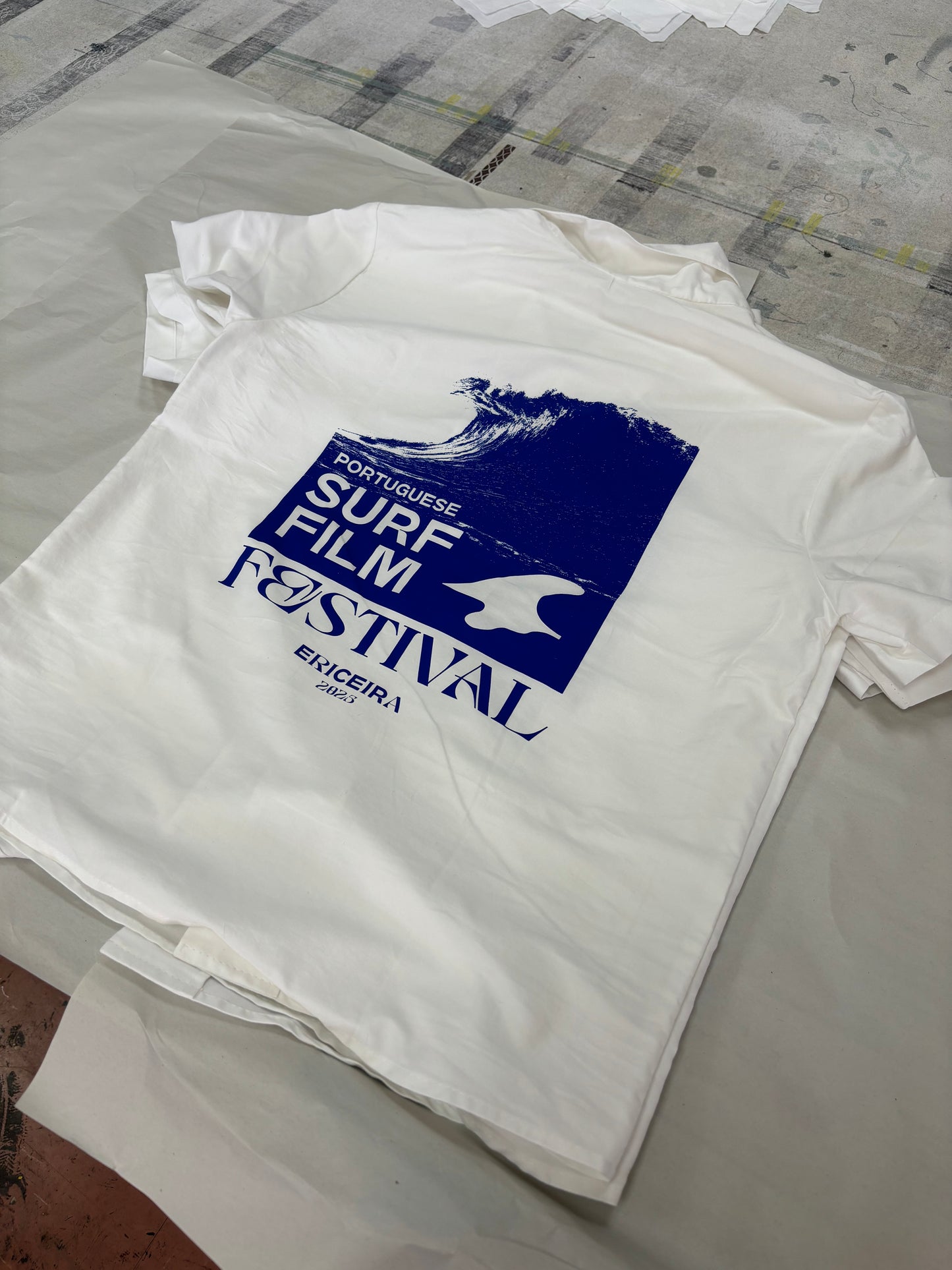 White t-shirt with blue graphic design on a textured surface
